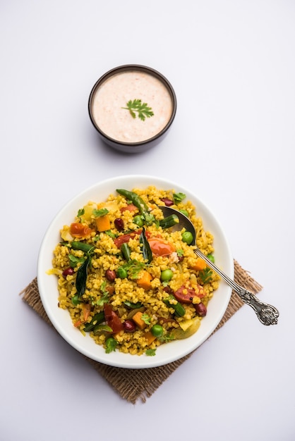 Broken wheat or Daliya Upma, served in a bowl. selective focus