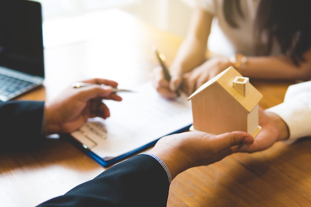 Broker giving keys of new house and handshaking with customer