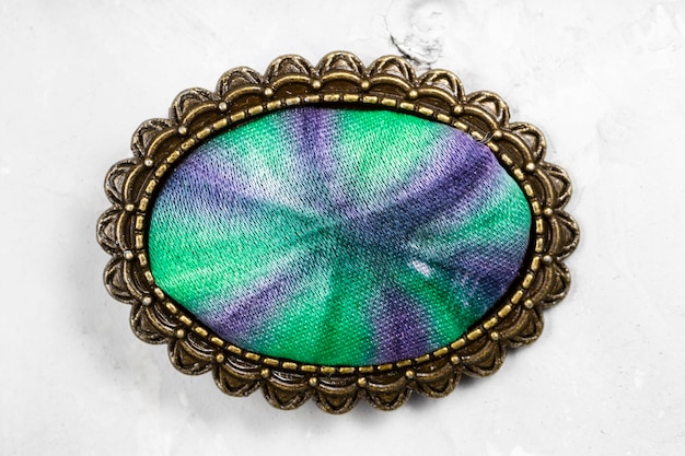 Bronze brooch with handcolored silk batik on gray