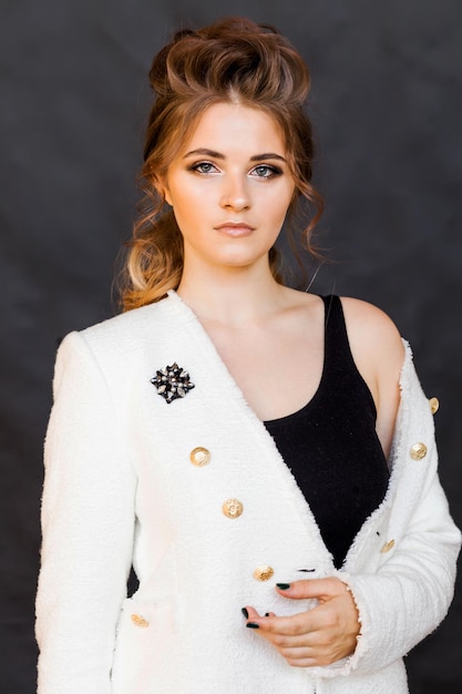 A brooch in the form of a medal on a white jacket of a young brunette woman