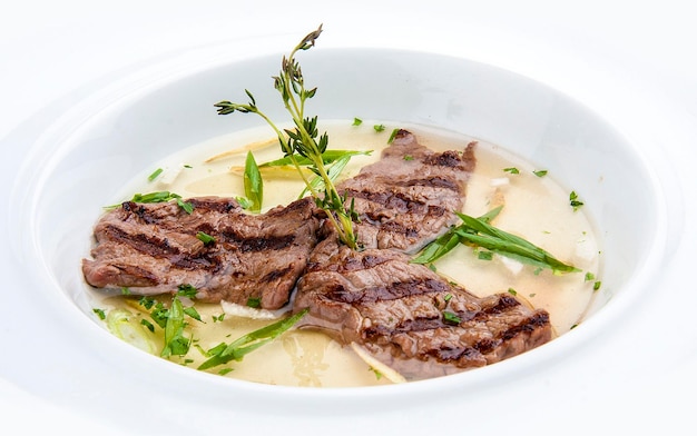 Broth with fried veal on white background