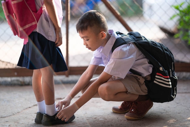 Brother helping sister wearing shoes before go to school on morning