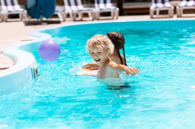 Brother laughing while playing ball with sister in pool