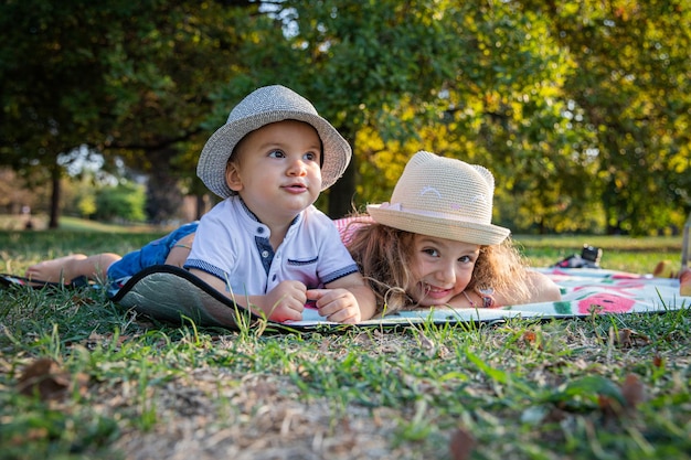 Brother and sister are lying on their stomachs during a picnic and having fun young siblings togetherness concept