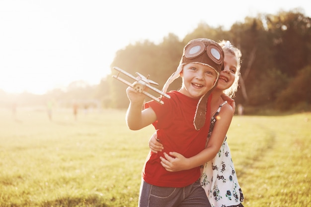 Brother and sister are playing together. Two children playing with a wooden airplane outdoor