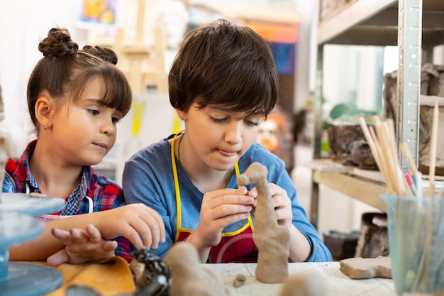 Brother and sister at the art lesson modeling clay animals