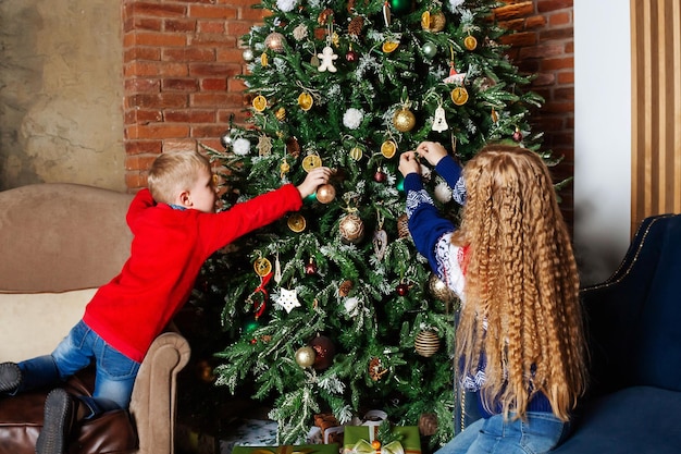 Brother and sister decorating together christmas tree