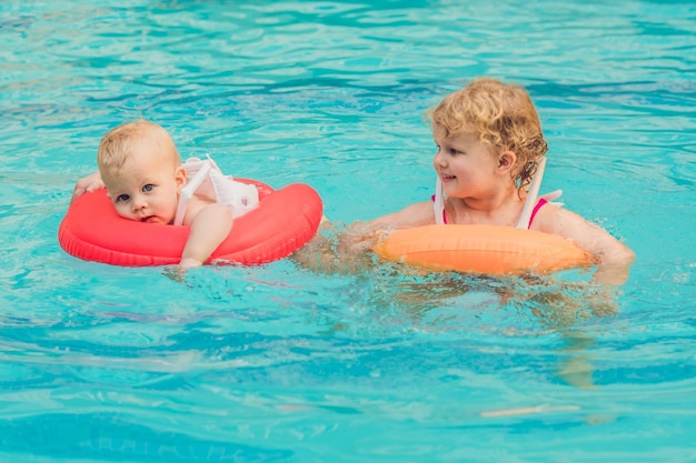 Brother and sister having fun in the pool in inflatable circles