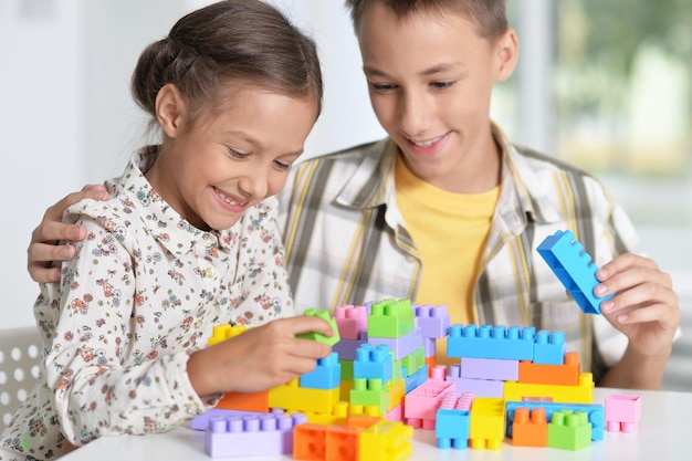 Brother and sister playing with colorful plastic blocks together