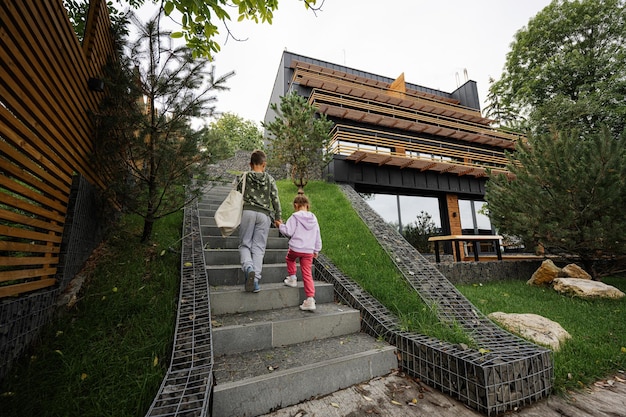 Brother with sister walking on stairs against modern wood stone house