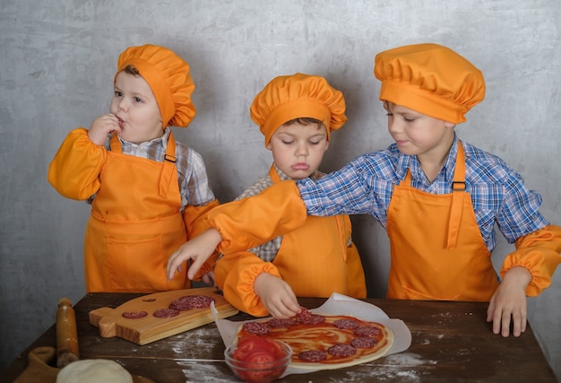 brothers help mom to cook pizza with sausage and cheese