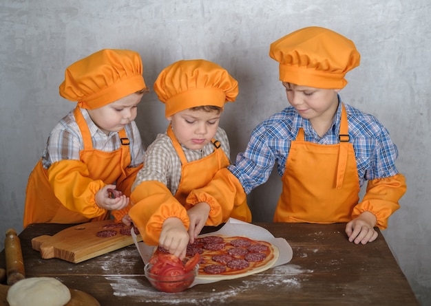 brothers help mom to cook pizza with sausage and cheese