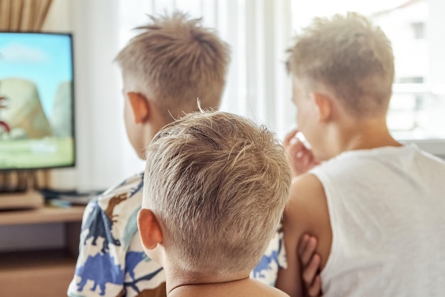 Brothers sitting in hotel room together watch cartoons on TV