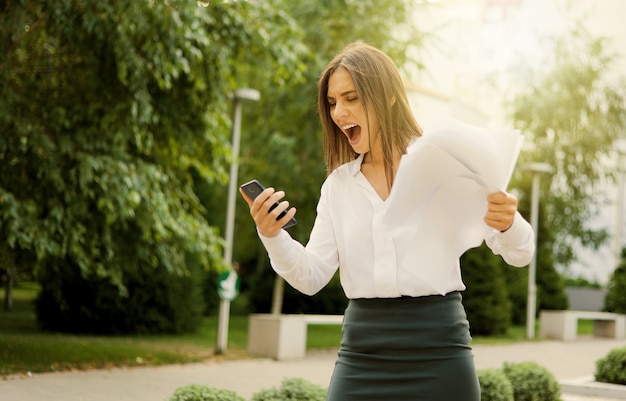 Brought to hysteria, angry business woman dressed in a white blouse and a skirt