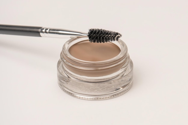 A brow pomade in blonde shade with brush isolated on a white background