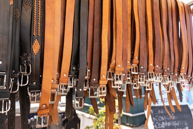 Brown and black leather belts hanging on street market stall Handmade accessories concept