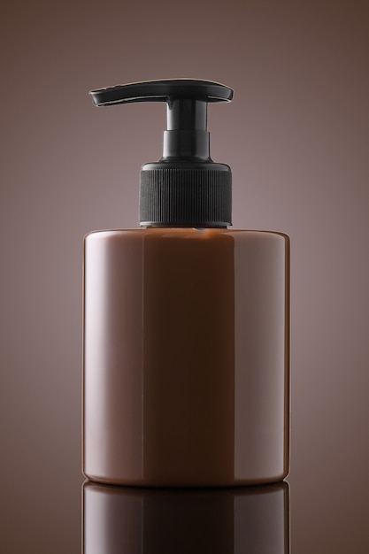 Brown bottle of liquid soap or gel on a chocolate background. A bottle of intimate soap on glass.