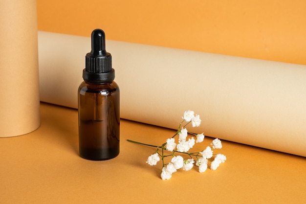 Brown bottle with cosmetic liquid on orange surface