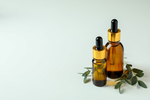 Brown bottles of eucalyptus oil and twigs on white background