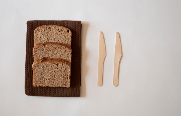 Photo brown bread slices with a knife on a white background minimal flat lay