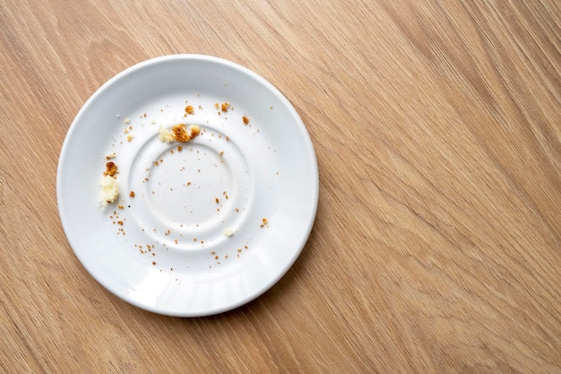 Brown cake crumbs on round white plate top view