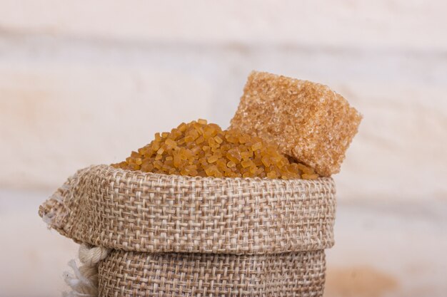 Brown cane sugar in a bag with a cube of shed on top