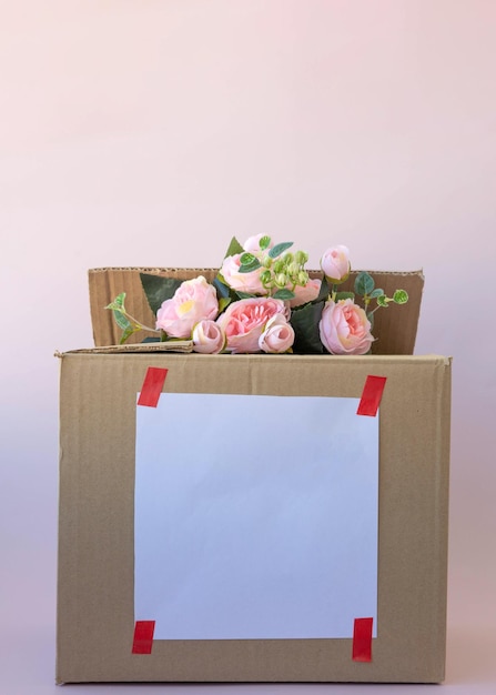 In a brown cardboard box pink flowers ecofriendly packaging a place for text