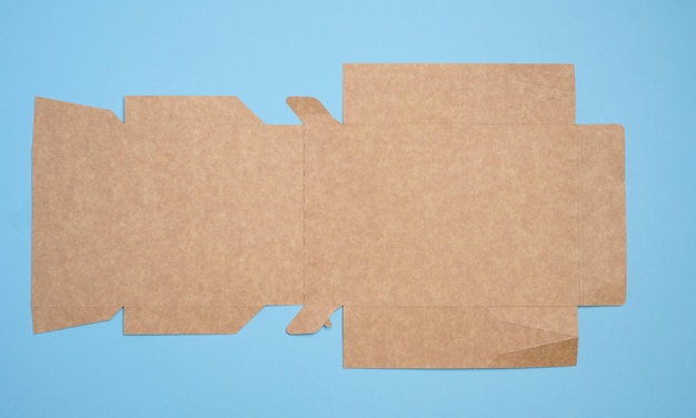 A brown cardboard box in an unfolded state on a blue background food packaging merchandise top view