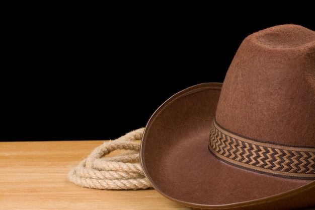 Brown cowboy hat and rope isolated on black