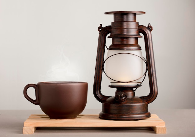 Brown cup of coffee with hot steam on desk with sunlight lamp yellowish orange background