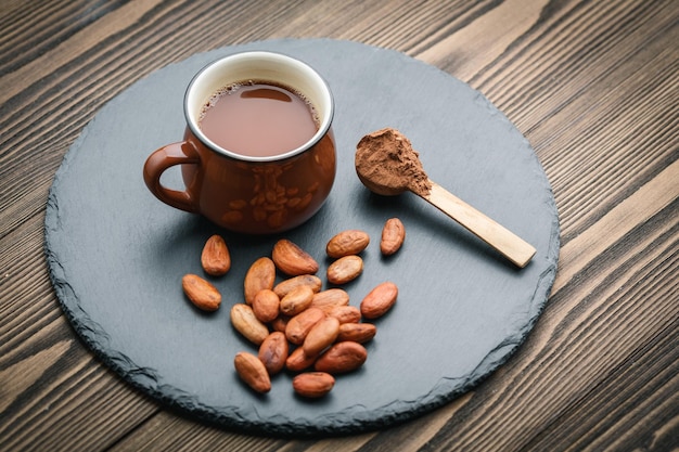 Brown cup of fresh cocoa drink with cocoa beans and powder