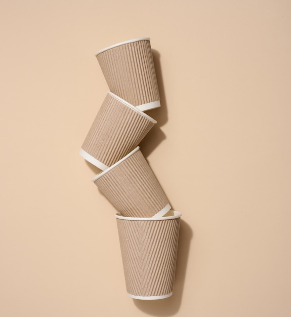 Brown disposable cups for coffee and tea on a beige background top view