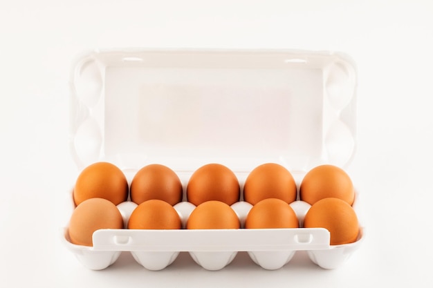 Brown eggs in plastic package on white background