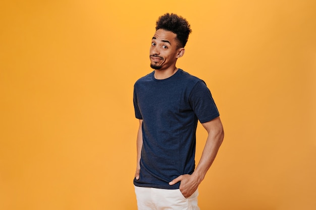 Brown-eyed man stares in surprise at camera on orange wall