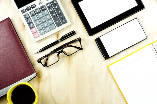 Brown eyeglasses and blank screen smartphones and tablet PC on the wooden desktop 