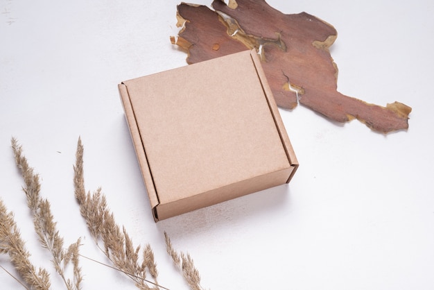 Brown flat cardboard carton box decorated with dried leaves, top view