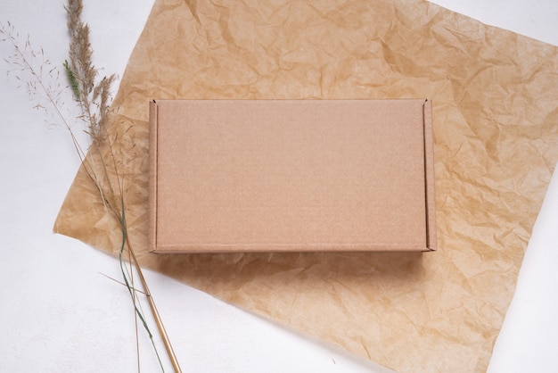 Brown flat cardboard carton box decorated with dried leaves, top view