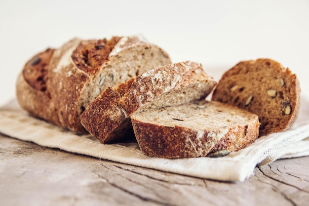 Brown fresh bread with seeds are cut into pieces on old wood background. Copy, empty space for text