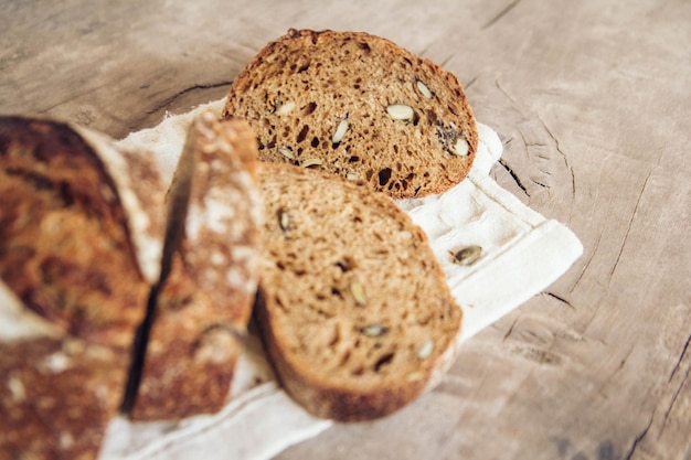 Brown fresh bread with seeds are cut into pieces on old wood background. Copy, empty space for text