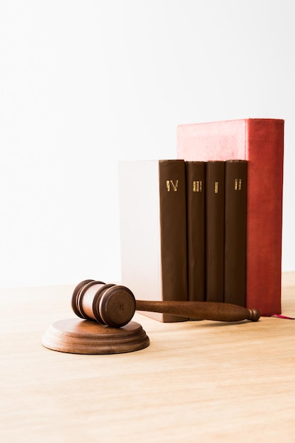 Photo brown gavel near row of red and brown books on wooden table isolated on white