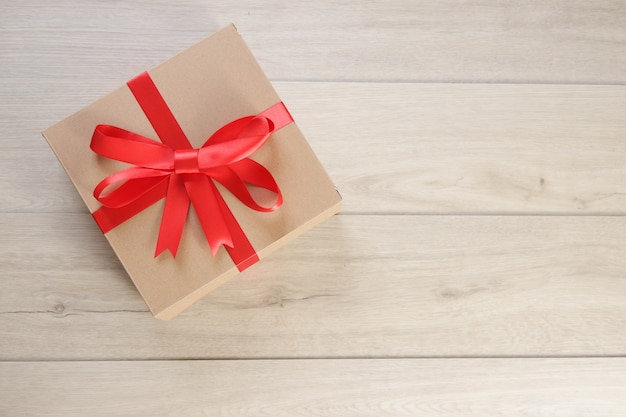 Brown gift box and red ribbon on wooden table