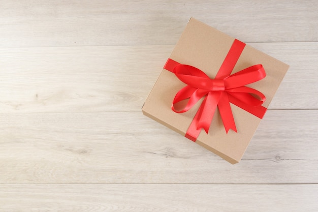 Brown gift box and red ribbon on wooden table