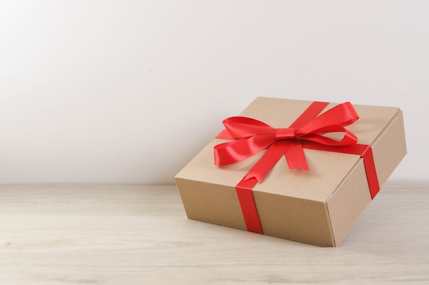 Brown gift box and red ribbon on wooden table