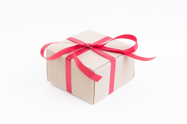 Brown gift box with red ribbon on white