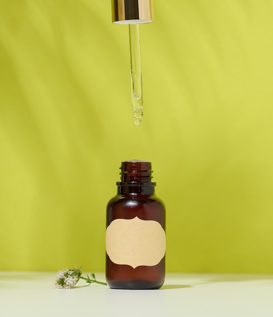 Brown glass bottle with a cosmetic product and a pipette green background Container for oils