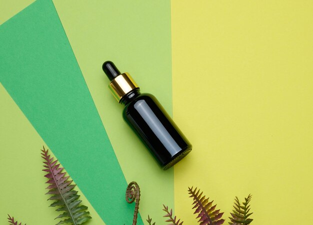 Photo brown glass bottle with a pipette on a green background template for cosmetic liquid products advertising and promotion