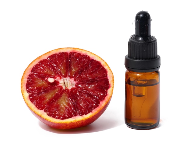 Brown glass bottle with a pipette and half of a red orange on a white background oils and cosmetics