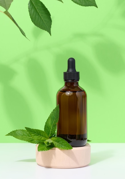 Brown glass bottle with pipette and mint leaves container for aromatic oils and cosmetics