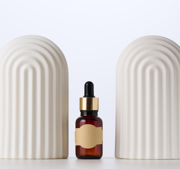 Brown glass bottle with a pipette stands on a white background Container for cosmetics serum and oil