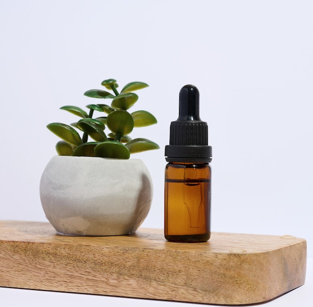 Brown glass bottle with a pipette on a wooden stand white background